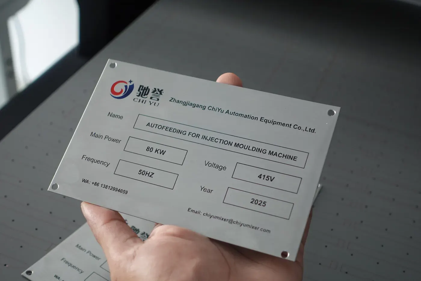 Stainless steel equipment rating plate held in hand